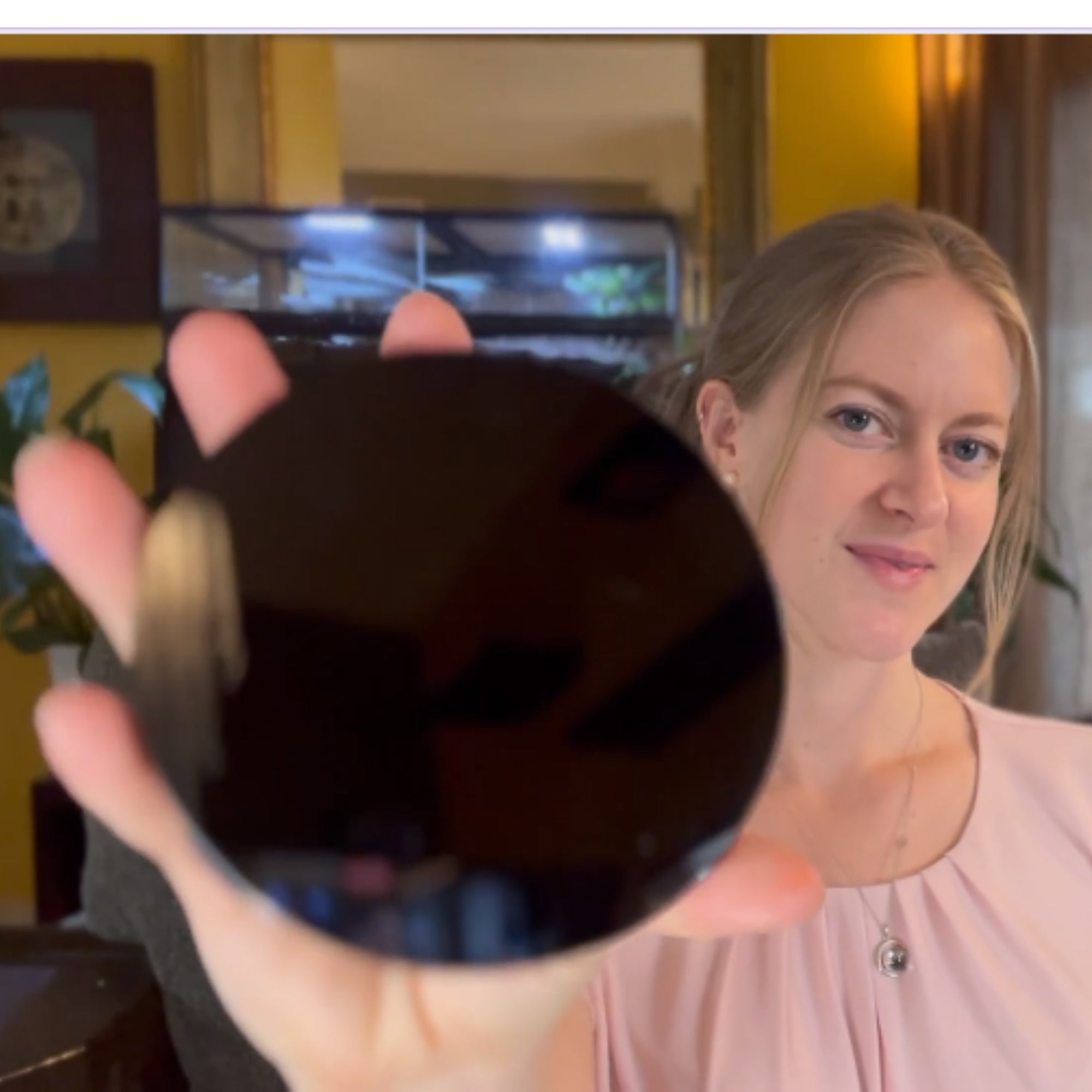 Hand holding a polished natural black obsidian mirror
